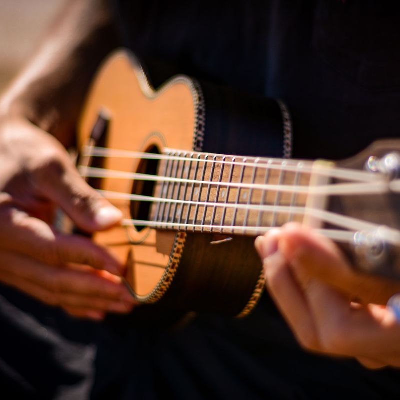 Close-up of hands strumming a wooden ukulele