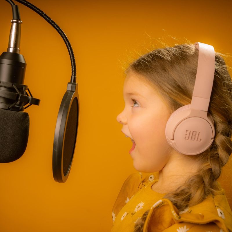 A young singer wearing headphones at a studio microphone